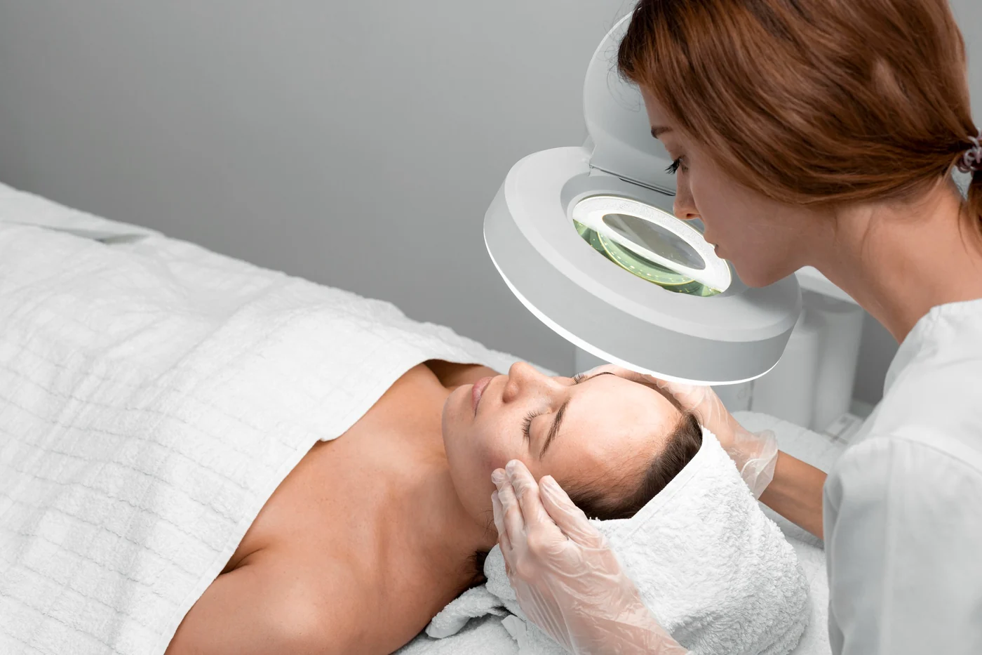 A therapist examining a client’s skin under a magnifying lamp before a rejuvenation treatment at Soma Laser and Skincare Clinic in Pretoria